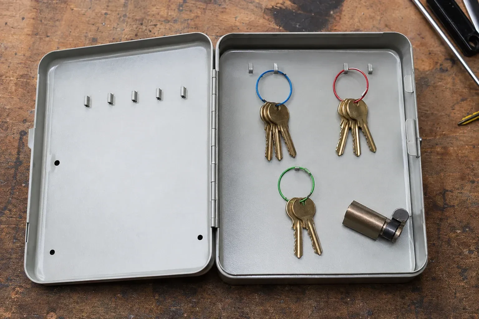 Three groups of keys on colored rings in an open metal key cabinet. — Master Key System Design, Peterborough